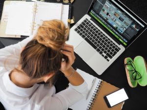 woman with head in hands at work, hungover and unproductive